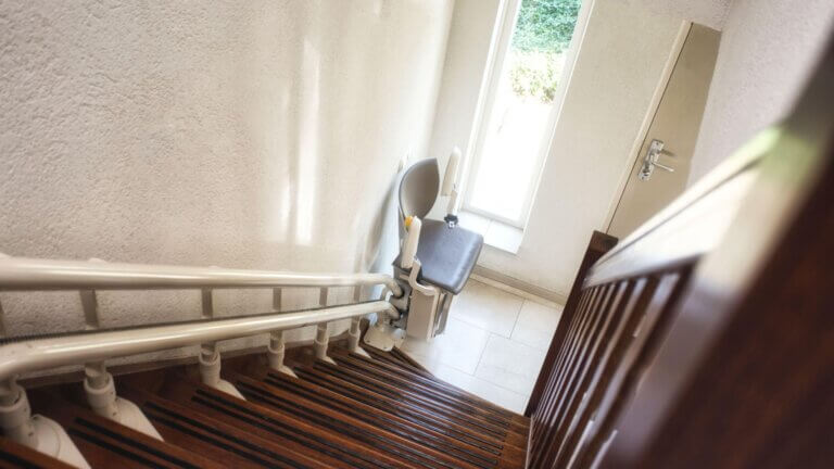 Stairlift on a wooden staircase near a window.