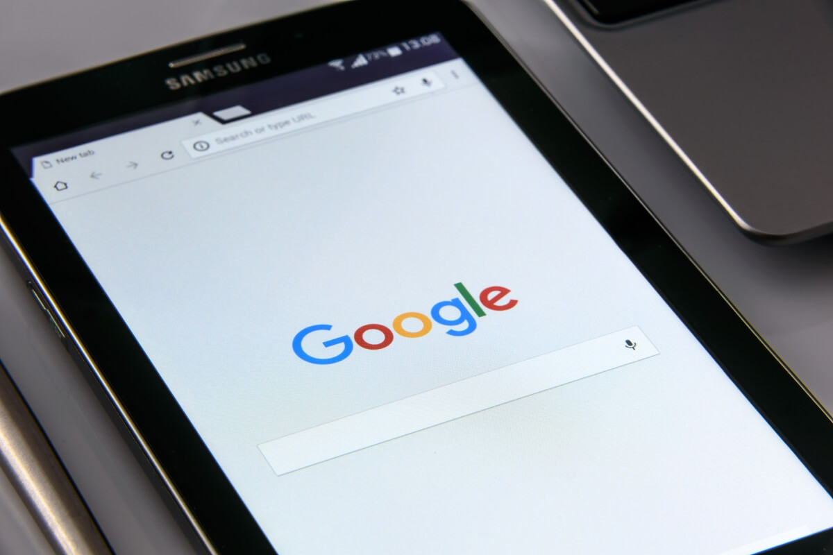 A tablet displaying the Google search homepage next to a laptop.