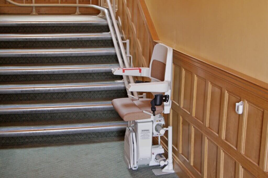 A view looking down a narrow, tightly winding spiral staircase made of dark wood steps and white balusters.