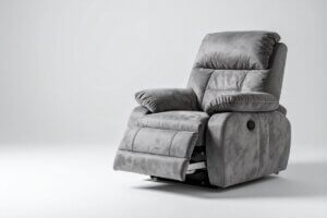 A studio shot of a plush grey suede electric recliner chair with its footrest slightly elevated.